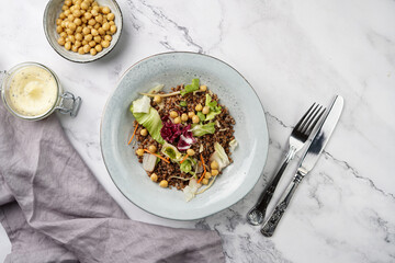 grey porcelain scandi soup bowl with traditional east european dish buckwheat salad with butter and chickpeas on marble surface and kitchen towel, top view, copy space