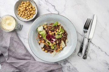 grey porcelain scandi soup bowl with traditional east european dish buckwheat salad with butter and chickpeas on marble surface and kitchen towel, top view, copy space