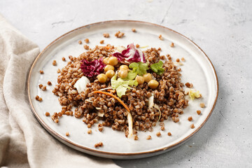 grey porcelain scandi plate with traditional east european dish buckwheat salad with butter and chickpeas on concrete surface