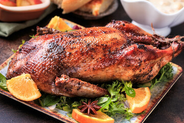 Traditional roasted stuffed Duck. Baked duck with oranges served with sauces, over dark background, top view. 
