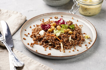 grey porcelain scandi plate with traditional east european dish buckwheat salad with butter and chickpeas on concrete surface