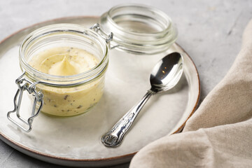 Mason jar with tasty herb butter with grated truffles on scandi plate on grey concrete surface