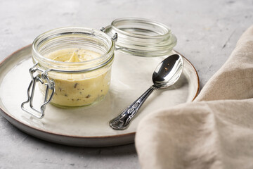 Mason jar with tasty herb butter with grated truffles on scandi plate on grey concrete surface