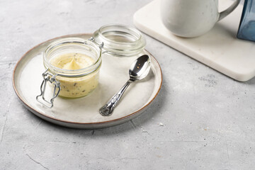 Mason jar with tasty herb butter with grated truffles on scandi plate on grey concrete surface