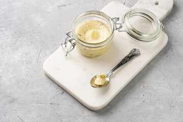 Mason jar with tasty herb butter with grated truffles on scandi plate on grey concrete surface