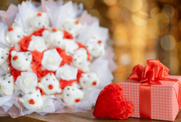 A gift with a red heart and a bouquet of toys on a background with bokeh. Selective focus.