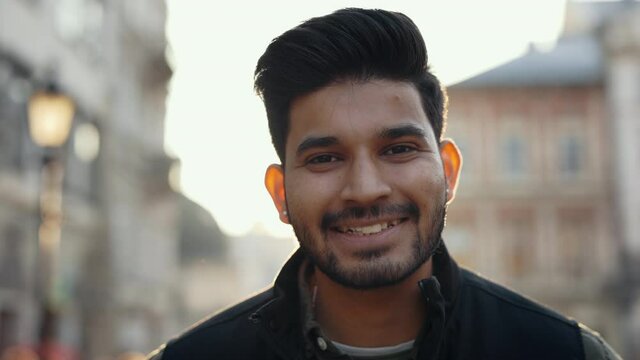Indian guy standing outdoors and smiling on camera