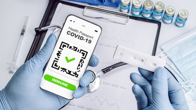 Covid passport doctor holding. Coronavirus vaccination certificate of immunity passport on smartphone screen with doctor stethoscope, syringe and medical equipment on hospital white background.