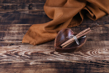 Cinnamon sticks in a wooden bowl on a wooden table