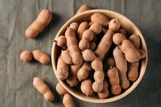 Fresh Tamarind fruits (Tamarindus indica, Indian date) Sweet ripe tamarinds on dark wood background. close-up