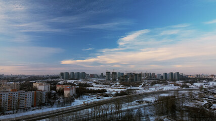 Flying over a snowy park. The city is visible on the horizon. Aerial photography.