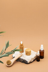 Fototapeta na wymiar Blank amber glass and bamboo essential oil bottles with pipette, glass spray bottle and bamboo jar on natural stone podium. Organic spa cosmetic beauty product mock up.
