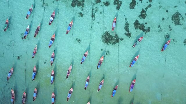 Aerial view of stunning summer landscape. A group of fishing long tail boat in turquoise Andaman sea and white sand beach at Koh Lipe or Lipe island, Satun, Southern Thailand. 4K drone video