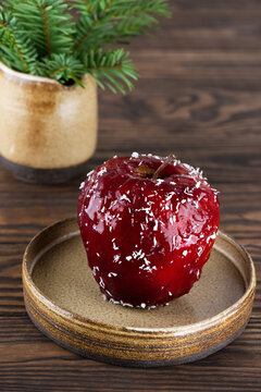 Red apple with walnuts and honey in glaze and coconut flakes on a wooden table.