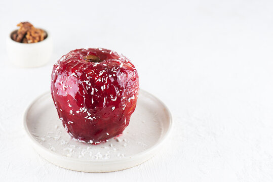 Red apple with walnuts and honey in glaze and coconut flakes on a light table. Horizontal orientation, copy space.