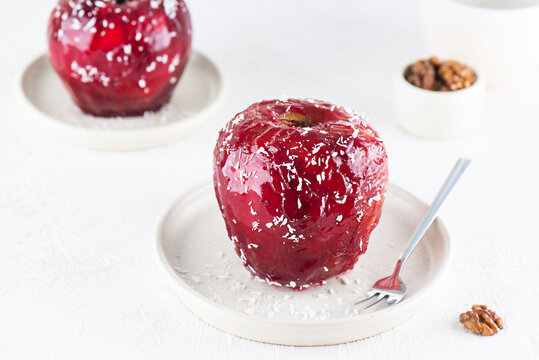 Red apples with walnuts and honey in glaze and coconut flakes.