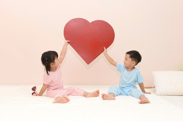 happy little Asian boy and girl with a red heart over pink background. valentines day concept