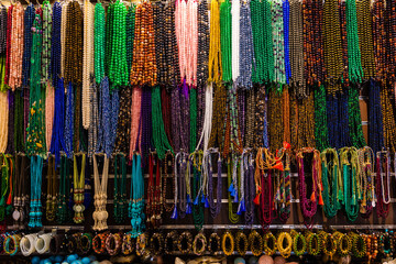 A range of colorful Handicraft bead necklaces and bangles hanging from the string in a shop. Close...