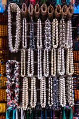 A range of colorful Handicraft bead necklaces and bangles hanging from the string in a shop. Close up shot of the colorful jewels.