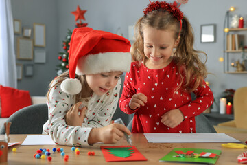 Cute little children making beautiful Christmas greeting cards at home