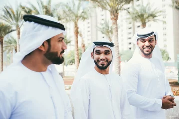 Fotobehang Group of business managers from the emirates meeting and working together in Dubai. Arabian businessmen wearing traditional clothes © oneinchpunch