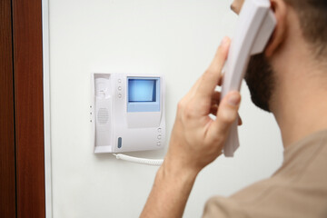 Man with handset answering intercom call indoors