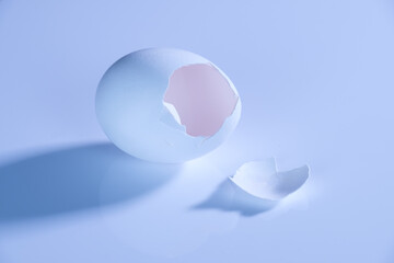 Eine weiße offene leere Eierschale / offenes Ei auf einem hellen neutralen Hintergrund (Symbol)