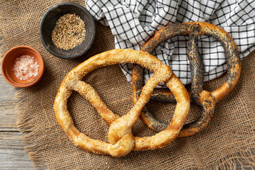 Large pretzels with sesame seeds and poppy seeds on a light gray wooden culinary background top view	
