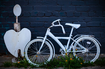 Fototapeta na wymiar an old decorative bicycle painted white stands against the wall
