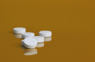 Several white pills on a yellow background. Classical medicine. Close-up. bokeh.