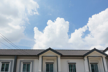 Gray tile roof on house in front of a clear blue sky on a sunny day background.