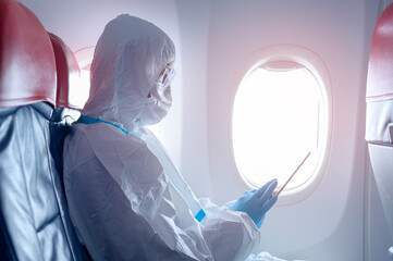 Fototapeta An Asian man is wearing protective suit , PPE suit in airplane , safety travel concept . obraz