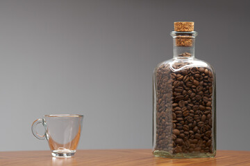 Empty glass espresso cup and bottle of coffee beans. - 480382377