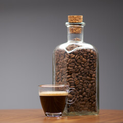 Glass cup of espresso and bottle of coffee beans.   - 480382382