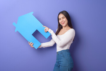 Portrait of beautiful woman  is holding blue  home on purple background