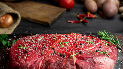 Raw beef steak seasoned with salt, pepper and fresh hearbs
