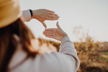 Close up of woman hand framing view distant over sunset. business concept, copy space