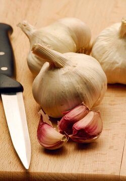 Fresh garlic spice vegetable on cutting wood table and kitchen knife.