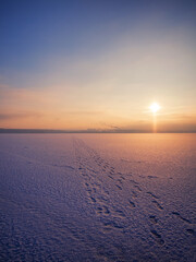 Sunset over a frozen and snow covered river on a winter morning. Winter sunset snow river