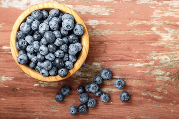 Blueberry berries are in a wooden plate on wooden background. Healthy food and healthy lifestyle.