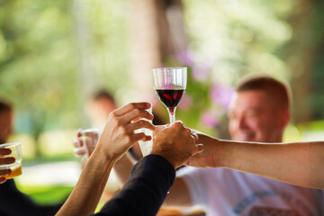 Wine glasses in the hands of people at a party. Detail of hands while toasting with glasses of wine. Happy people at a party.
