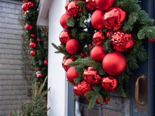 Beautiful red Christmas ornaments on a green wreath on a storefront window