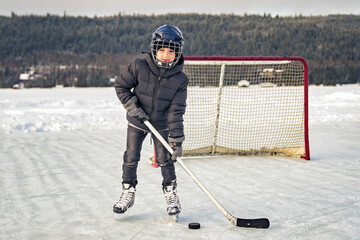 Boy playing hockey on a beautiful lake - Powered by Adobe