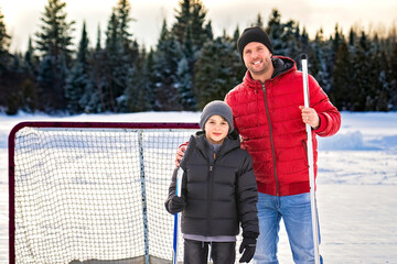 Father and son playing hockey together outside on a lake