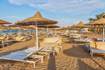 Hurghada, Egypt.  Buildings, swimming pools and a recreation area by the red sea. Umbrellas and sun loungers on an empty beach .Lounge chairs and Umbrellas early morning