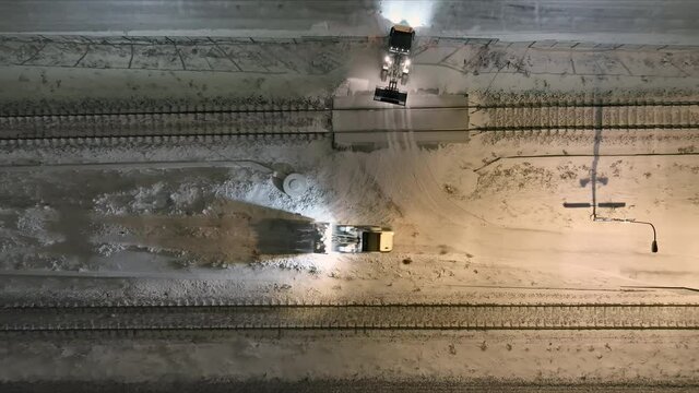 Vantaa.Finland-December 29.2021: Small tractors clearing snow off of the train tracks in Vantaa. Maintaining transportation during the scandinavian winter. Aerial shot. Camera pointed downwards.