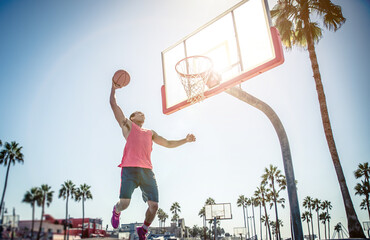 Young players playing basketball at the court in venice beach, California. Professional street ballers having fun performing tricks and huge slam dunks © oneinchpunch