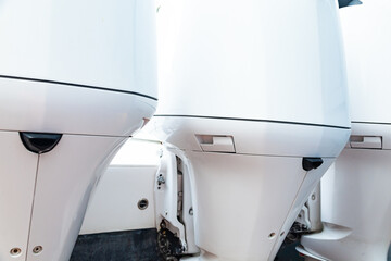 Three white outboard motors mounted at the stern of the motorboat.