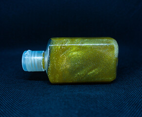 Shining golden liquid in a transparent bottle on a black background