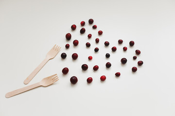 Heart made of cranberries and bamboo fork on white background top view